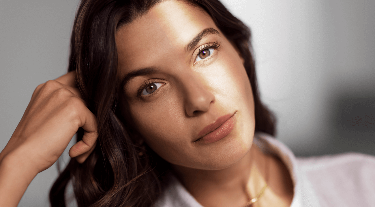 Close-up portrait of a brunette woman with healthy-looking skin, soft makeup, and a relaxed expression, highlighting natural beauty and facial radiance.
