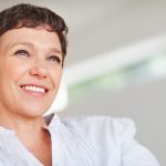 Smiling middle-aged woman with short brown hair and a relaxed expression, representing confidence, well-being, and women's hormonal health during perimenopause and menopause.