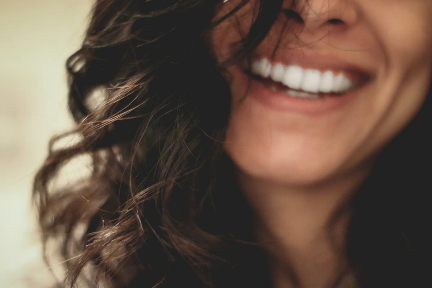 Close-up of a smiling woman with wavy brown hair and a natural, joyful expression, highlighting beauty and confidence.
